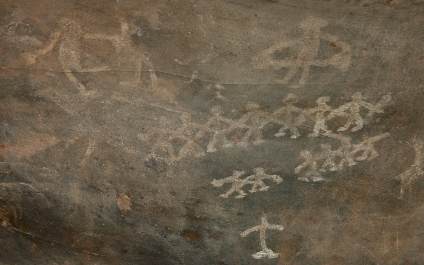 A prehistoric rock painting of about twenty figures moving together, used as a marker for a group without a permanent ruler