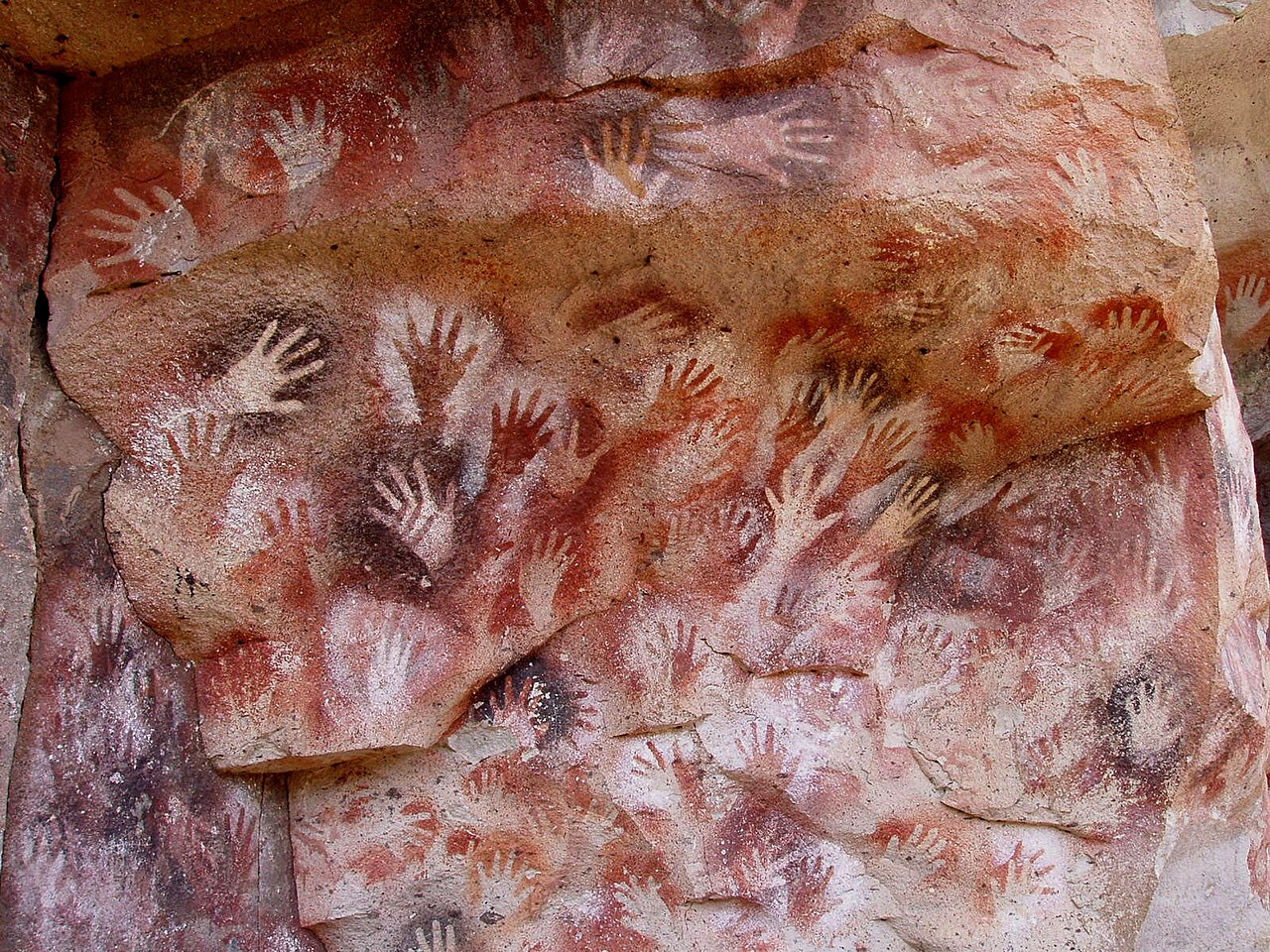 Prehistoric hand paintings covering a cave wall at Cueva de las Manos